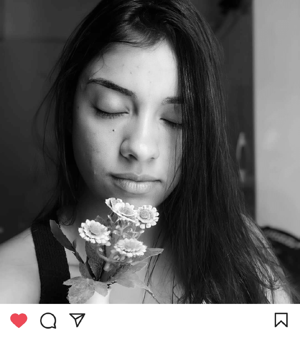Kamila em uma fotografia em preto e branco, segurando pequenas flores